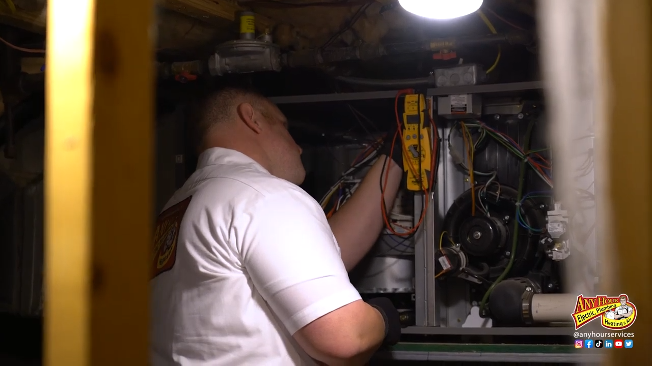 A technician is working on an HVAC unit, measuring with a multimeter, with company logo visible.