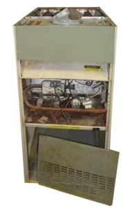 Old furnace with its front panel removed, revealing internal wiring and components. The exposed metal parts show signs of rust and wear.