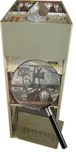 Old electric furnace with exposed wires, viewed through magnifying glass. The image conveys a sense of caution and need for repair.