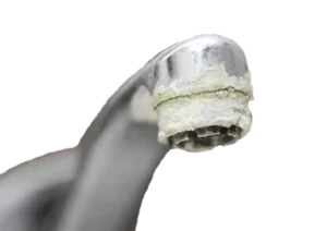 Close-up of a chrome faucet with heavy white limescale buildup around the spout. The image emphasizes the need for cleaning and maintenance.
