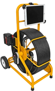Yellow inspection camera system with a large coiled cable on a two-wheeled frame. A tablet is mounted on top and a battery pack is attached to the side.