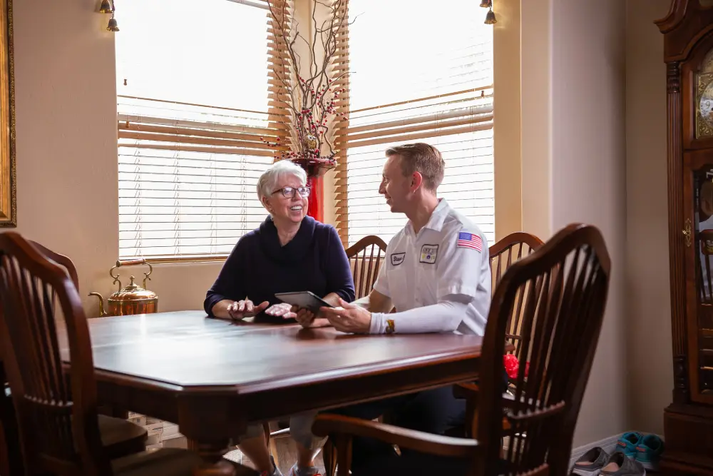 woman speaking with an Any Hour Services technician, sitting at a table.